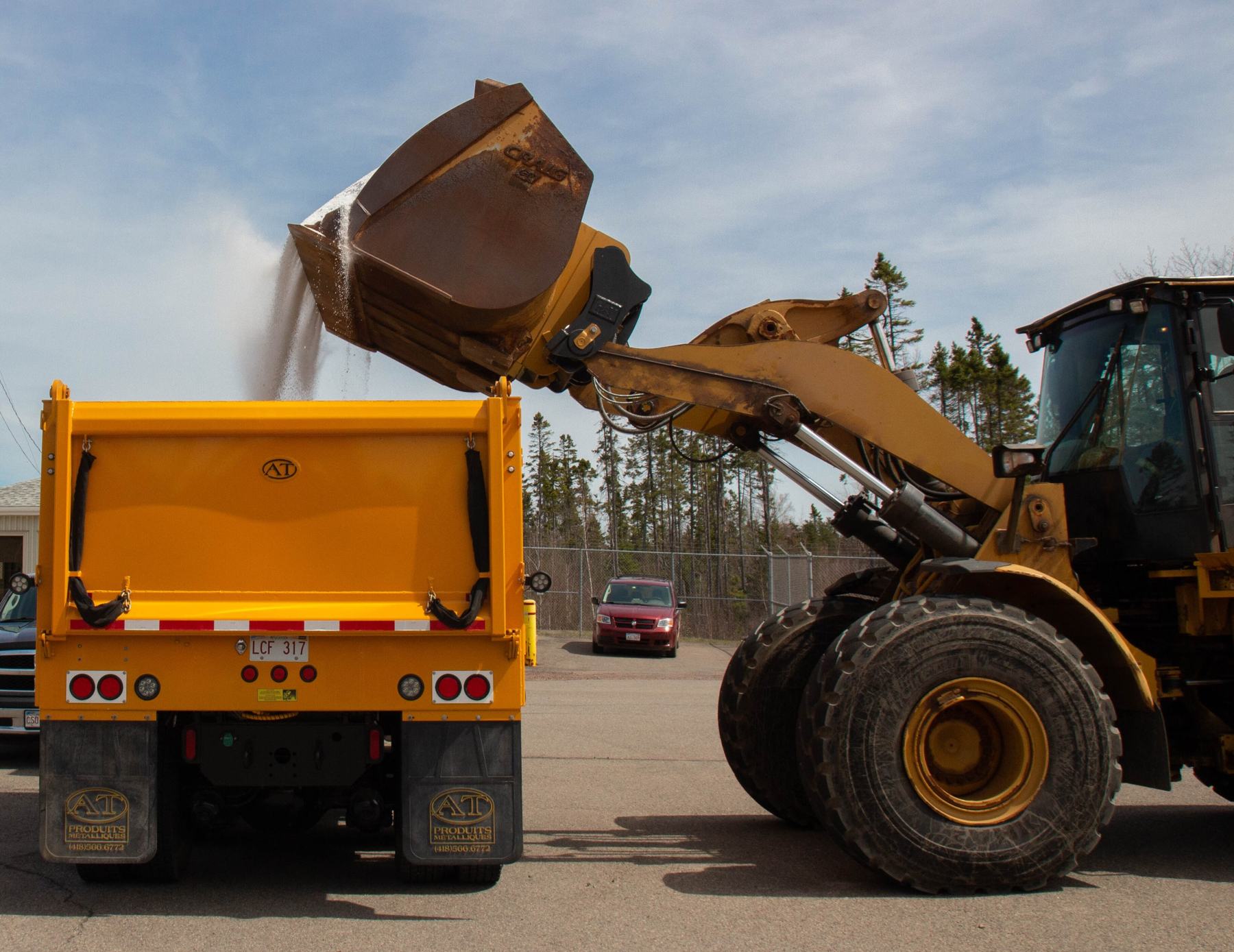 Wheel loader dumping road salt into a dump truck